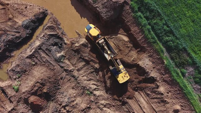  Vista a&eacute;rea de gr&uacute;a excavadora realizando descarga sobre el dumper en cantera de aridos  mientras se revela el impacto ambiental de la cantera