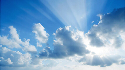 Dramatic blue sky with sun rays shining through fluffy white clouds © saeed