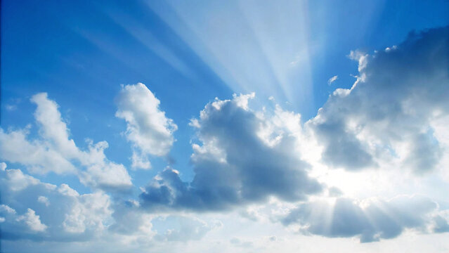 Dramatic blue sky with sun rays shining through fluffy white clouds