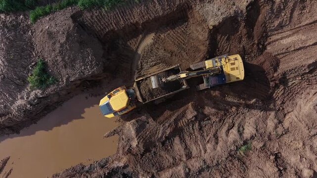 Acercamiento sobre la cantera: gr&uacute;a descarga sobre el dumper mostrando el impacto ambiental
