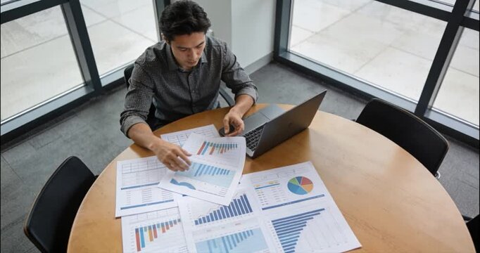 Man analyzing financial data at a round table with a laptop