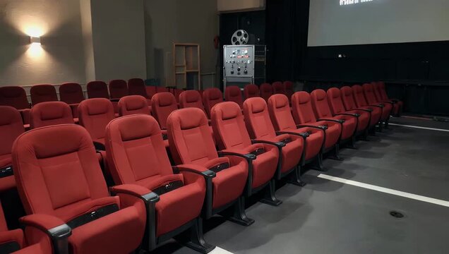 High quality 4K interior footage of empty modern cinema theater showcasing rows of plush red seats and dramatic quiet atmosphere before movie screening