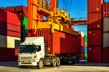Container handling. Container truck picking up container at yard. Port logistics, container yard operation. © Kosal