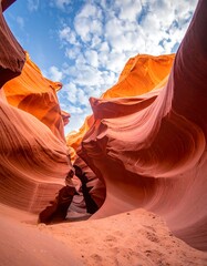 Eroded orange sandstone canyon walls reach for a blue sky with white clouds