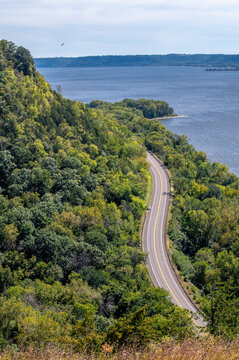 Winding Great River Road (Highway 35) along Maiden Rock Bluff, Wisconsin, with green forest, river, sandy bend, and scenic natural landscape.