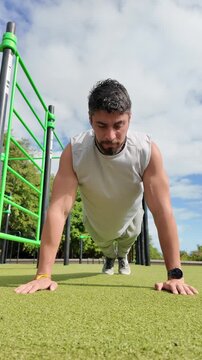 Young man doing push-ups workout in park outdoors