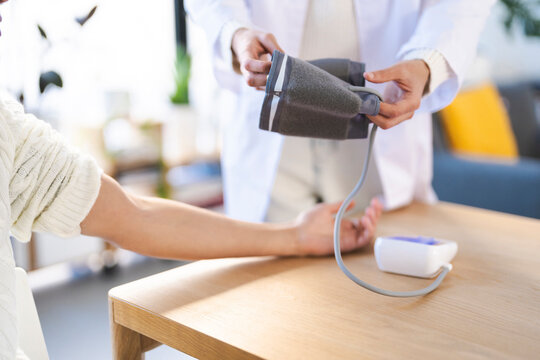 A medical professional in a white coat takes a patient's blood pressure with a digital monitor.