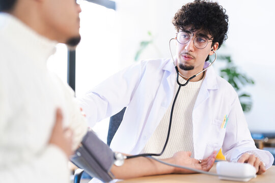 A doctor in a white coat uses a stethoscope and blood pressure cuff to examine a patient.