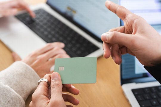 Hands using a credit card and typing on a laptop, representing online transactions and digital payments.