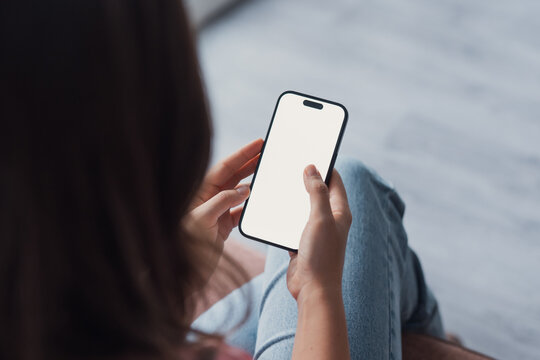 Close up of female hands holding phone with white blank space. Woman using phone in office with laptop on the background. Shopping online insurance concept