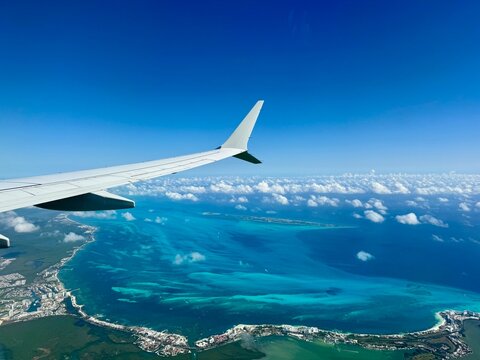 Window view of airplane wing above Mexican coastline including Cancun hotel zone and Isla Mujeres in Quintana Roo, Yucatan Peninsula, Mexico