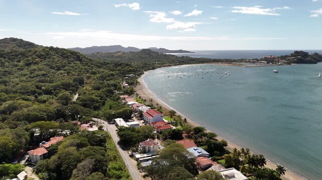Aerial turning shot of distant Playa Flamingo and marina with boats anchored off the coast of Costa Rica.
