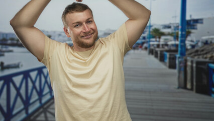 Obraz premium Man with bare arms stretching on a promenade by the seaside, eyes closed and smiling; relaxation leisure.
