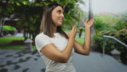 Naklejka premium Woman pointing finger toward railing on a building entrance walkway in a garden setting; curiosity discovery.