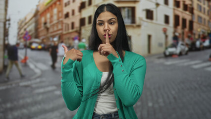Fototapeta premium Woman hand pointing at passing cars on a sunlit urban street lined with historic buildings; quiet reflection.