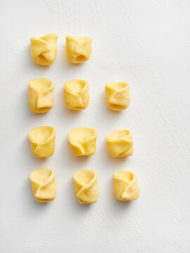 This image showcases freshly made tortellini arranged neatly in two rows. Ideal for use in food blogs, restaurant menus, or culinary advertisements focused on Italian cuisine