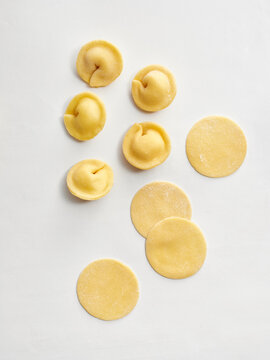 Freshly made pasta dumplings and circles arranged on a clean surface. Ideal for use in cooking blogs, restaurant menus, or culinary advertisements
