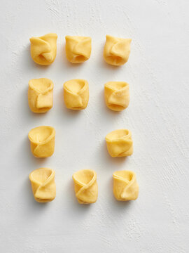The image shows neatly arranged raw tortellini on a white surface. This visual is great for restaurant menus, food blogs, social media posts, and culinary advertisements