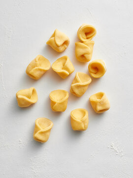 The image shows rows of fresh handmade tortellini arranged on a white background. Ideal for restaurant menus, cooking blogs, and advertising Italian cuisine