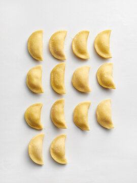 Fresh uncooked dumplings are arranged in a precise formation on a light surface. This setup is ideal for restaurant menus, food blogs, and culinary advertisements