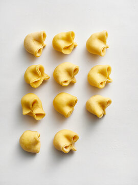 The image shows freshly made pasta shapes on a clean white surface. Ideal for use in culinary websites, restaurant menus, or food-related advertising