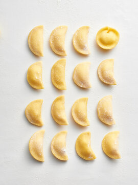 The image showcases a variety of handmade dumplings beautifully arranged in rows on a clean surface
