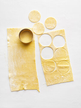 The image shows fresh pasta dough being rolled out and cut into circles. This visual is ideal for cooking websites, menus, and food blogs focusing on Italian cuisine