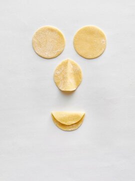 Dough pieces are arranged on a white surface, showcasing various shapes for dumpling making. Ideal for food blogs, cooking tutorials, restaurant menu designs, and culinary advertisements