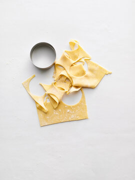 The image shows fresh pasta dough pieces alongside a round cutter. Ideal for use in recipe books, cooking blogs, culinary classes, and food advertisements