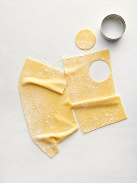 Fresh pasta sheets are rolled out with circular cutouts made using a metal cutter. Ideal for cooking videos, recipe blogs, and culinary workshops