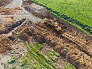 Aerial panorama of heavy machinery in civil works, dumper truck and excavator coordinating earthmoving. © Ivanb