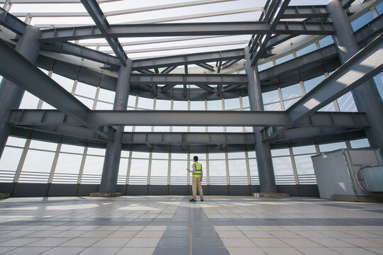 Worker in safety vest inspecting steel structural observation platform while looking upward