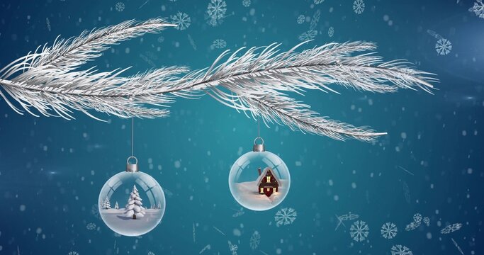 Hanging glass baubles on frosty pine branch on teal backdrop showing tree, lit cabin, snow falling