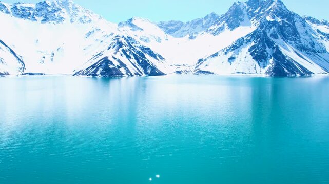 Drone flyover above turquoise water at El Yeso Reservoir in winter.