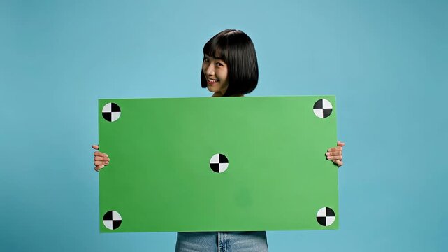 Smiling young woman holding green blank sign with tracking dots