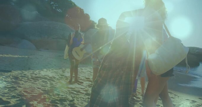 Friends arriving on cove, arranging cooler, guitar, towel under lens flare, creating marketing