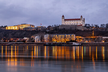 Bratislava Castle at dusk above the Danube with city lights in Slovakia