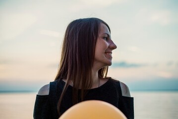 Side profile portrait of smiling young woman with balloon at sunset © Bohdan