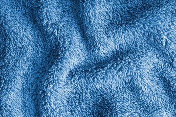 Close up, macro of crumpled blue terry towel fabric with wrinkles and soft waves. Fluffy microfiber texture with dense fibers, textile, material structure, detailed cloth abstract background © katyamaximenko