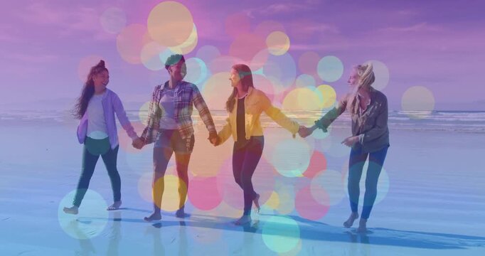 Four women holding hands walking on wet sand, bokeh growing and veiling reflections for marketing
