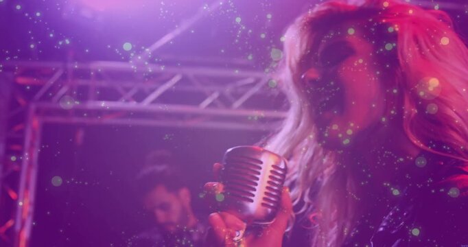 Woman singer pressing retro mic singing music, cam moving back revealing band, bokeh around singer