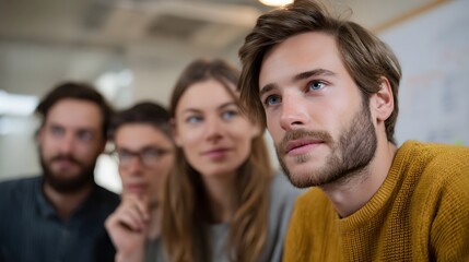 Obraz premium A group of diverse young professionals focused intently on a presentation or discussion in a modern office environment