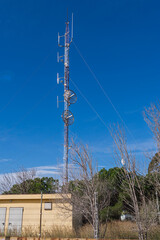 Obraz premium Telecommunications tower with parabolic antennas against clear blue sky.