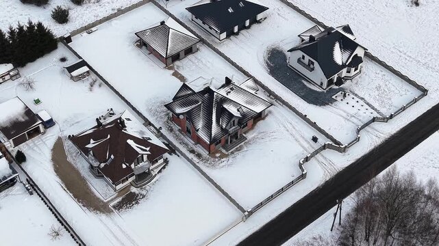 Aerial winter neighborhood showing roof snow melting differences