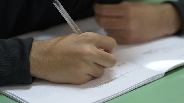 Student Writing Notes in Notebook During Lesson