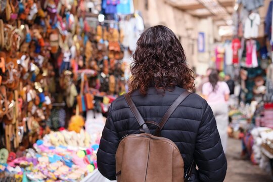 Woman walking through marrakech souk market with backpack