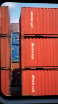Motion blur view of various colorful shipping containers passing by the window of a moving train during a logistics transport operation