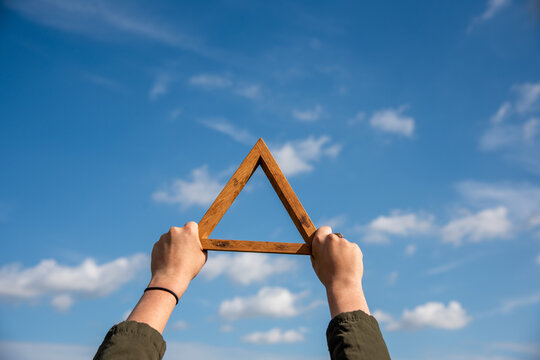 Hands holding wooden triangle skyward