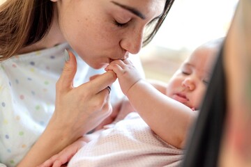 Tender mother kissing baby's hand.