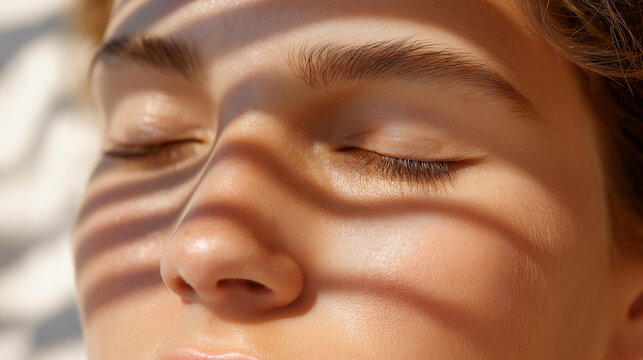 Warm sunlight casting soft shadow patterns across an unrecognizable face with closed eyes, beauty and skincare concept, natural light photography, calm aesthetic, with copy space